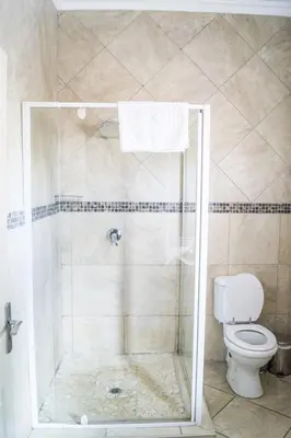 a bathroom with a shower with a toilet at Ivory Lodge Bendor in Polokwane