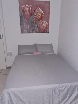 a white bed in a room with a painting on the wall at Streetview Suites in Polokwane