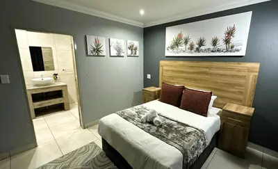 a bedroom with a bed and a bathroom with a sink at Khayalami Hotel - Ermelo in Ermelo