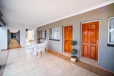 a dining room with a table and white chairs at Khayalami Hotel - Ermelo in Ermelo