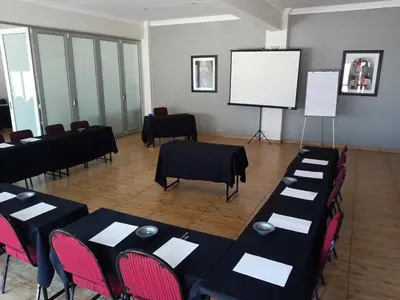 a conference room with black tables and chairs and a white screen at Khayalami Hotel - Ermelo in Ermelo