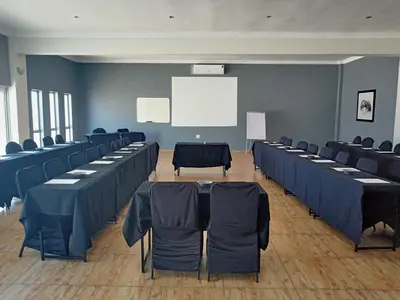 a conference room with tables and chairs and a white screen at Khayalami Hotel - Ermelo in Ermelo