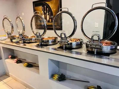 a counter with several pans of food on it at Khayalami Hotel - Ermelo in Ermelo