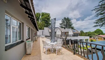 a patio with a table and chairs on a balcony at Khayalami Hotel - Ermelo in Ermelo
