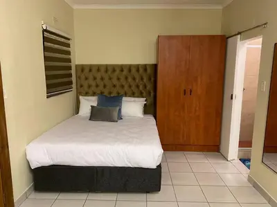 a bedroom with a bed and a wooden cabinet at The Royal Nest in Sandown