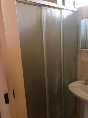 a shower with a glass door next to a sink at The Royal Nest in Sandown