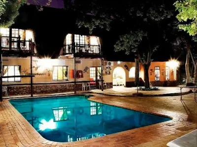 a swimming pool in front of a building at night at Lapalosa Lodge in Centurion