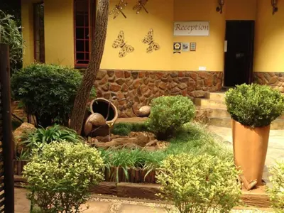 a garden in front of a building with a stone wall at Lapalosa Lodge in Centurion