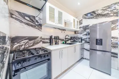 a kitchen with white cabinets and a stainless steel refrigerator at Homes of Ace Diamond in Pretoria