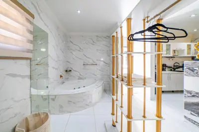 a bathroom with a tub and a glass shower at Homes of Ace Diamond in Pretoria