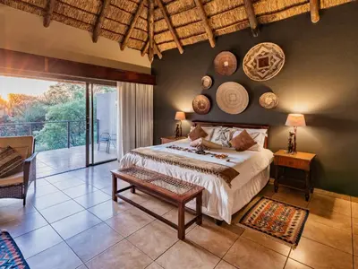 a bedroom with a large bed and a balcony at Sable Ranch Thaba Khaya Lodge in Brits