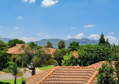 a roof of a house with trees and mountains in the background at 10 Pecanwood Dr 4 Bedroom Beauty in Hartbeespoort
