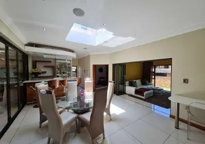 a dining room and living room with a glass table and chairs at 10 Pecanwood Dr 4 Bedroom Beauty in Hartbeespoort