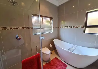 a bathroom with a tub and a glass shower at 10 Pecanwood Dr 4 Bedroom Beauty in Hartbeespoort