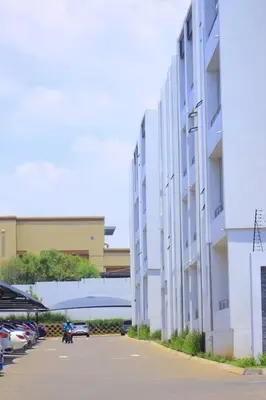 a white building with cars parked in a parking lot at Chic Home in Erand
