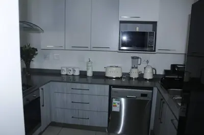 a kitchen with white cabinets and a microwave at Chic Home in Erand