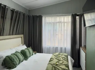 a bedroom with a bed with green pillows and a window at Wild Fig Rest Guest House in Polokwane