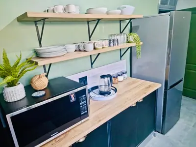 a kitchen with wooden shelves and a microwave at Wild Fig Rest Guest House in Polokwane