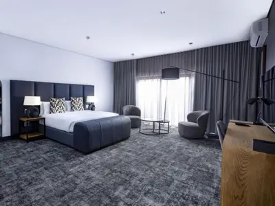 a hotel room with a bed and chairs and a television at Panorama Villa in Graskop