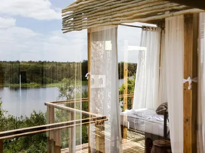 a room with a balcony with a view of a lake at Simbavati Hilltop Lodge in Timbavati Game Reserve
