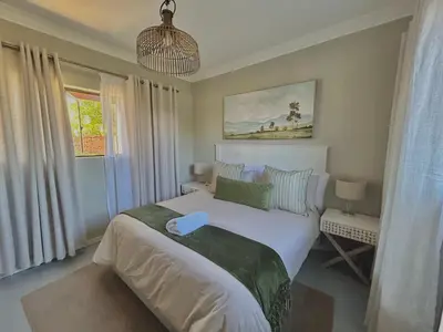a bedroom with a large white bed and a window at The Acorn @ Skyfall Country Estate in Polokwane
