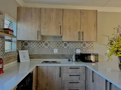 a kitchen with white counter tops and wooden cabinets at The Acorn @ Skyfall Country Estate in Polokwane