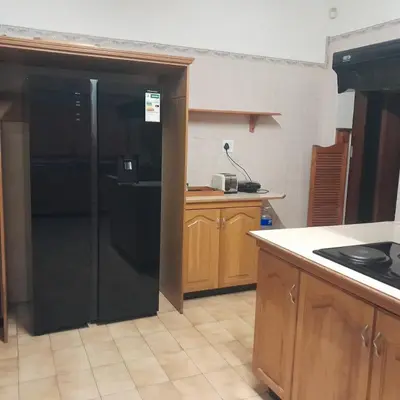 a kitchen with a black refrigerator and wooden cabinets at 38 On Andrew Street in Sabie
