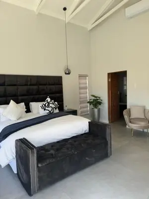 a bedroom with a large black bed and a chair at De Marea villa in Naboomspruit