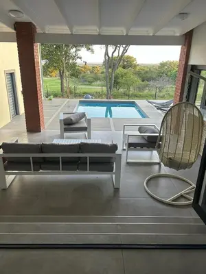 a patio with a couch and chairs and a pool at De Marea villa in Naboomspruit