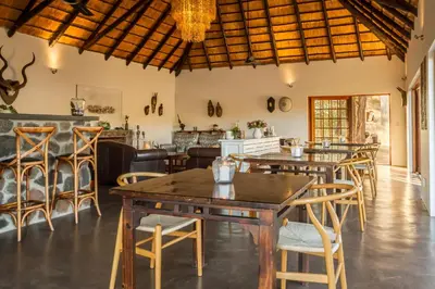 a restaurant with tables and chairs and a bar at Mbizi Bush Lodge in Grietjie Nature Reserve