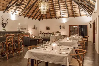 a restaurant with tables and chairs and a chandelier at Mbizi Bush Lodge in Grietjie Nature Reserve
