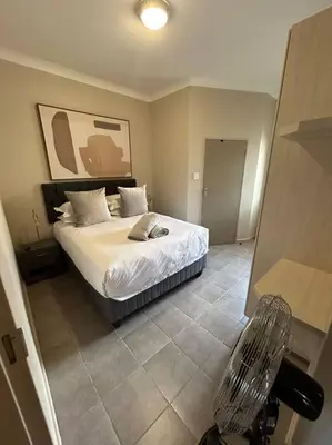 a bedroom with a bed and a chair in it at Home away from Home in Pretoria
