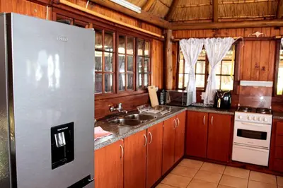 a kitchen with wooden cabinets and a stainless steel refrigerator at Stunning chalet with a dam view. in Vendaland