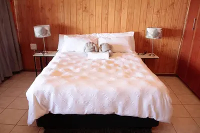 a bed with two teddy bears laying on it at Stunning chalet with a dam view. in Vendaland