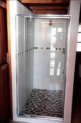 a man standing in a shower in a bathroom at Stunning chalet with a dam view. in Vendaland