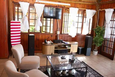 a living room with a tv and a table and chairs at Stunning chalet with a dam view. in Vendaland