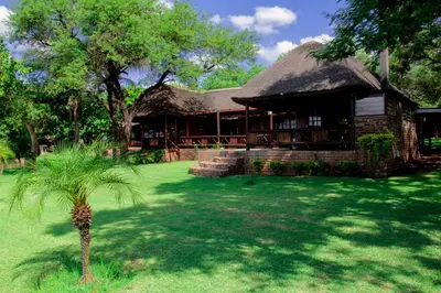 a building with a palm tree in front of it at Stunning chalet with a dam view. in Vendaland