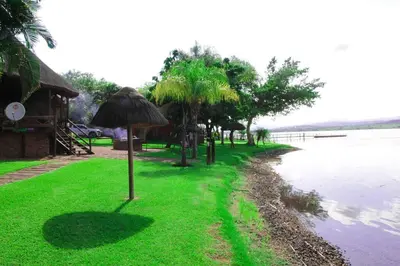 a grass umbrella on the side of a body of water at Stunning chalet with a dam view. in Vendaland