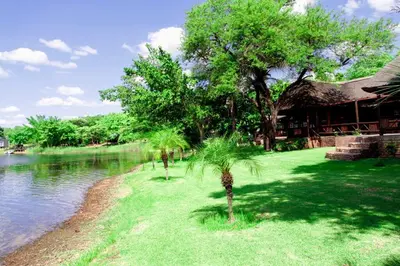 a resort with palm trees next to a body of water at Stunning chalet with a dam view. in Vendaland