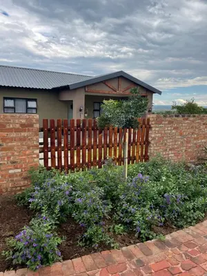 a fence in front of a house with flowers at The Cozy Nook @ Skyfall Country Estate in Polokwane