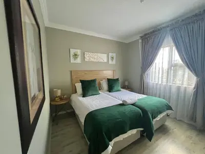 a bedroom with a bed with green pillows and a window at The Cozy Nook @ Skyfall Country Estate in Polokwane