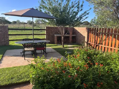 a picnic table with an umbrella in a garden at The Comfy Corner @ Skyfall Country Estate in Polokwane