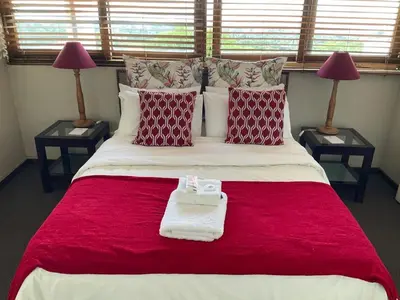 a bedroom with a large bed with red and white pillows at Jopasso Guest House in Pretoria