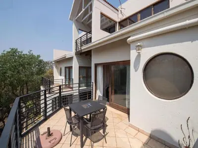 a patio with a table and chairs on a balcony at Jopasso Guest House in Pretoria