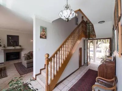 a staircase in a living room with a chandelier at Jopasso Guest House in Pretoria