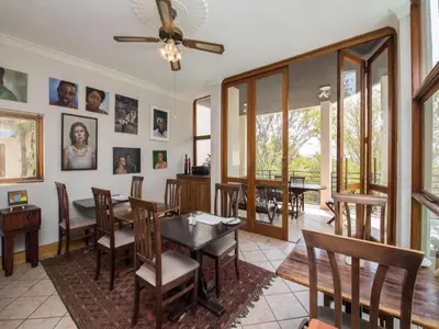a dining room with a table and chairs and windows at Jopasso Guest House in Pretoria