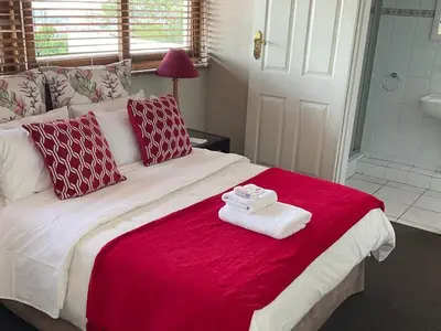 a bedroom with a large bed with red and white pillows at Jopasso Guest House in Pretoria