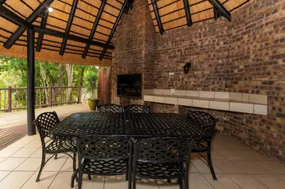 a patio with a table and chairs and a brick wall at Kruger Park Lodge Unit No. 216 in Hazyview