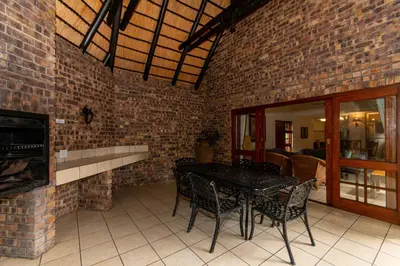 a dining room with a table and chairs and a brick wall at Kruger Park Lodge Unit No. 216 in Hazyview