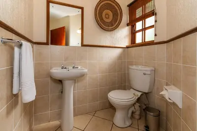 a bathroom with a toilet and a sink and a mirror at Kruger Park Lodge Unit No. 216 in Hazyview